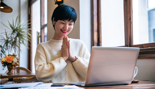 Asian woman looking pleased while looking at computer