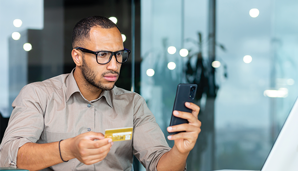 man holding credit card and phone